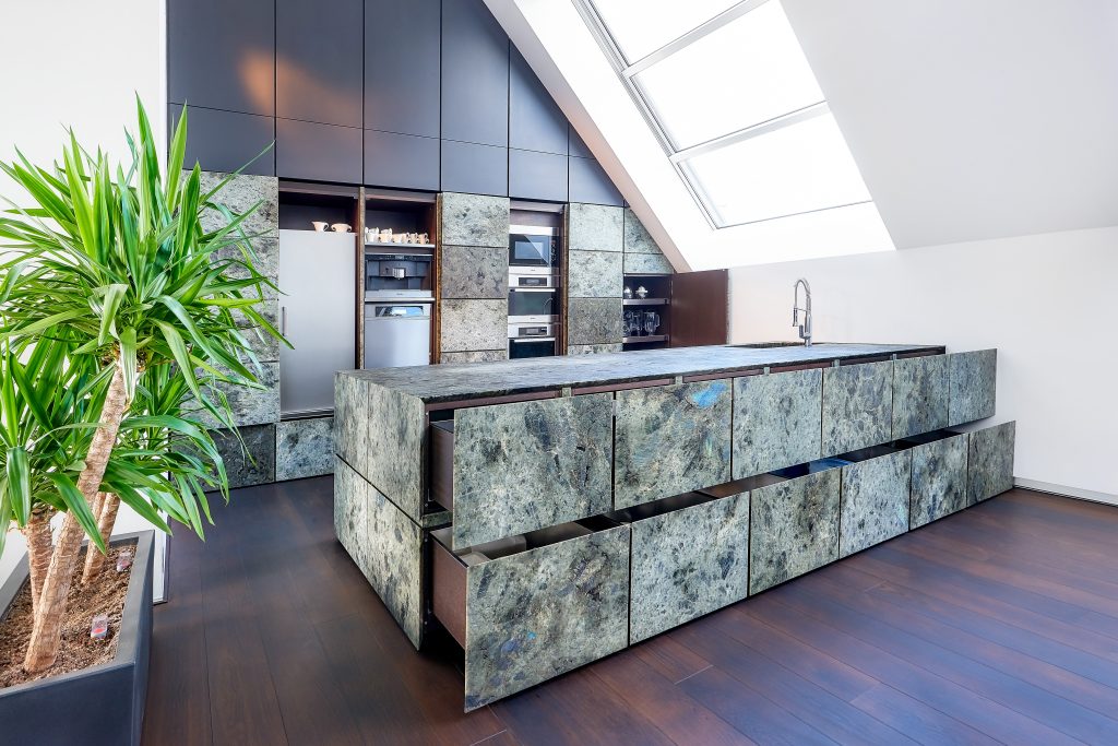 modern kitchen in natural stone, in this picture with all drawers and panels slightly open to reveal the appliances